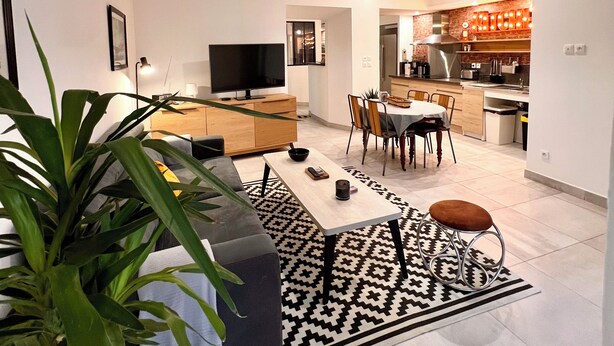 Ein modernes Wohnzimmer mit Sofa, Couchtisch und einer großen Pflanze.