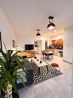 A modern living room with a sofa, coffee table, and a large plant. - Loft with Air Conditioning and Jacuzzi - Near Les Grands Buffets, Downtown (Narbonne)