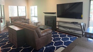 A living room with a fireplace, a large flat-screen TV, and a sectional sofa. - Tahoe Pines Escape (Incline Village)