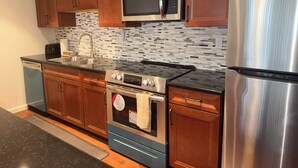 A modern kitchen with wooden cabinets, a stainless steel refrigerator, a built-in microwave, a stove, and a dishwasher. - Tahoe Pines Escape (Incline Village)