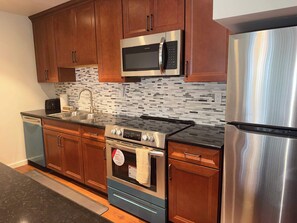 A modern kitchen with wooden cabinets, a stainless steel refrigerator, a built-in microwave, a stove, and a dishwasher. - Tahoe Pines Hideaway (Incline Village)