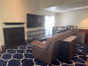 A living room with a fireplace, a television, a dining table with chairs, a sofa, and a small cabinet. - Tahoe Pines Hideaway (Incline Village)