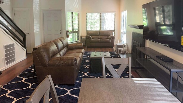 A living room with a brown leather sofa, a wooden coffee table, a TV, and a fireplace. - Tahoe Pines Escape (Incline Village)