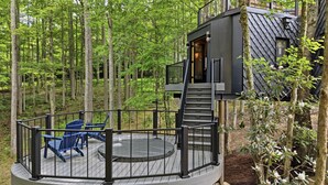 Una casa sull'albero con una terrazza circolare, una scala e sedie blu.