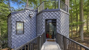 Una baita circondata da alberi, con una scala che conduce a una porta.