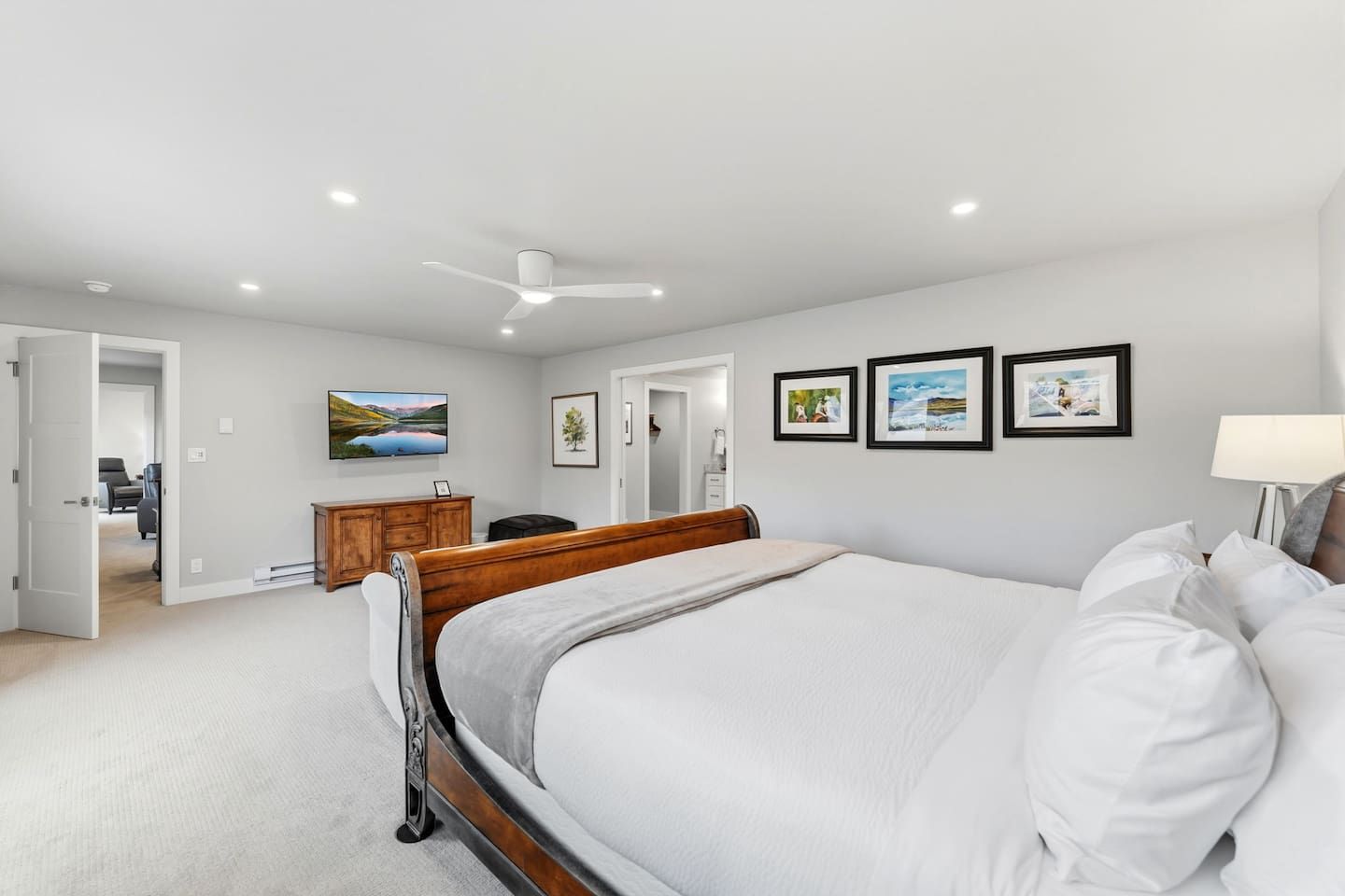 Une chambre à coucher avec un lit, une commode, un téléviseur et des tableaux encadrés accrochés au mur.