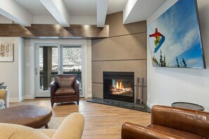 Ein modernes Wohnzimmer mit Kamin, Ledermöbeln und einem großen Fenster.