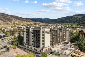 Un edificio residenziale a più piani con tetto piatto, immerso in un paesaggio collinare.