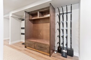 Ein Zimmer mit großem Holzschrank, Kleiderhaken und einem kleinen Heizgerät auf dem Boden.