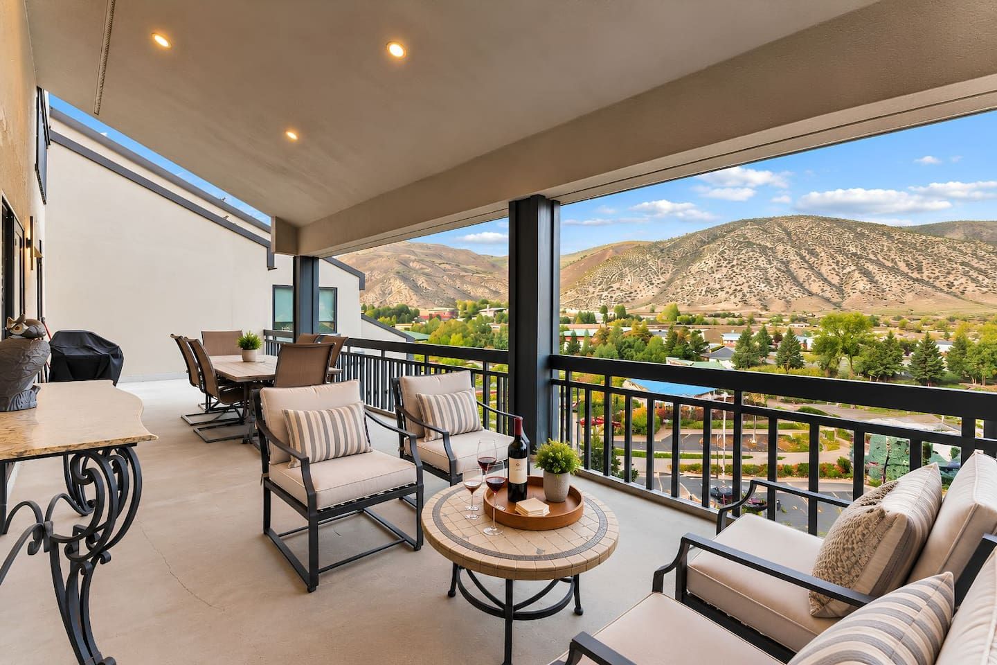 A balcony with a dining area, seating, and a view of a mountainous landscape.