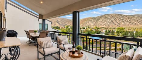 A balcony with a dining area, seating, and a view of a mountainous landscape.
