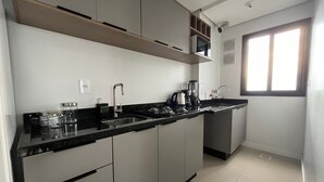 A modern kitchen with a black countertop, stainless steel appliances, and a window providing natural light.