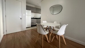 A modern kitchen with white cabinets, a white refrigerator, and a round mirror on the wall.
