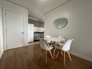 Una cocina moderna con armarios blancos, un refrigerador blanco y un espejo redondo en la pared.