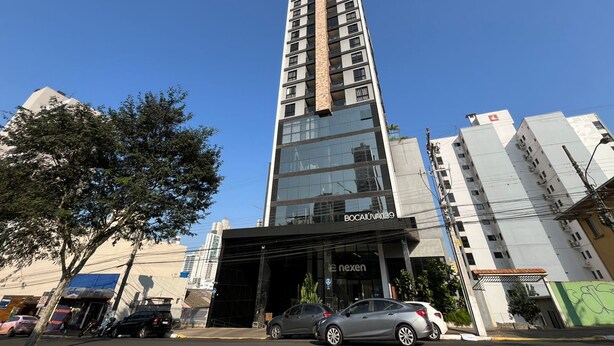 A tall building with a glass facade, a sign reading 'BOCAJUVA139', and a black entrance.