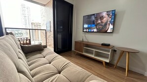 A modern living room with a sofa, TV, wooden TV stand, and a small table.