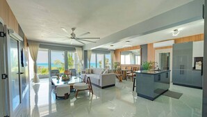 A spacious living area with a large sofa, a dining table, and a kitchen area with modern appliances.