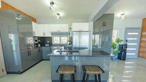 A modern kitchen with a central island, bar stools, and built-in appliances.