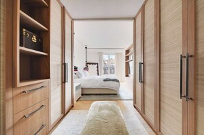 Quarto com cama, mesas de cabeceira, guarda-roupa e um banco.
