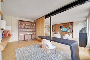 Ein modernes Wohnzimmer mit einem Holzregal, einem schwarzen Esstisch und einem weißen Sessel.