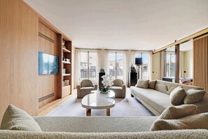 Ein modernes Wohnzimmer mit einer Couch, Sesseln, einem Couchtisch und einem Bücherregal.