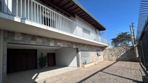 A two-story building with a balcony, a stone wall, and a paved driveway. - Hospedaria Campinas  (Campinas)
