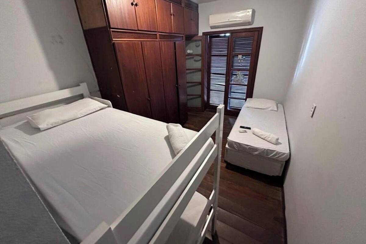 Ein kleines Schlafzimmer mit Etagenbett, einem Einzelbett, Holzschränken und einem fest eingebauten Kleiderschrank mit Spiegel.