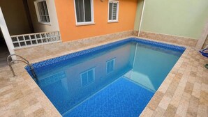 A rectangular swimming pool with a tiled edge, surrounded by a tiled floor and walls. - Hospedaria Campinas  (Campinas)