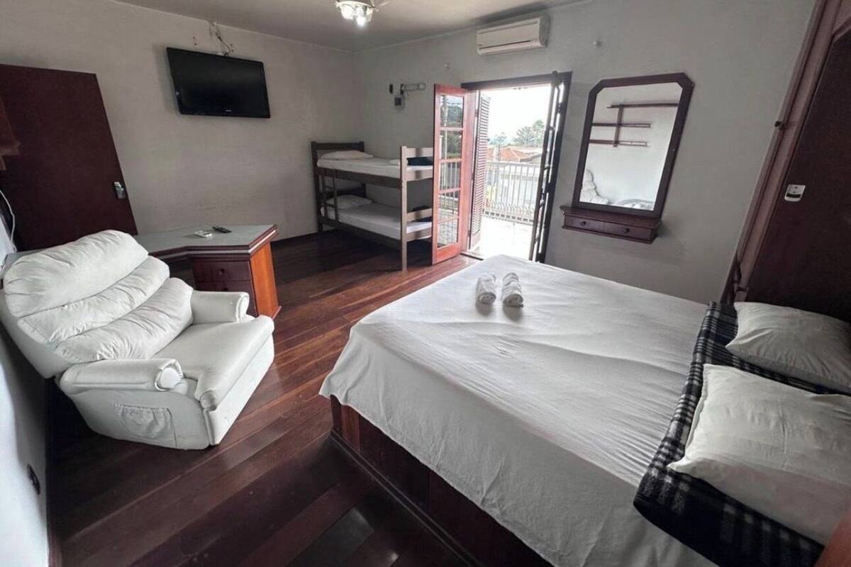 Ein Schlafzimmer mit Bett, Sofa, Schreibtisch, Fernseher und einem Balkon.