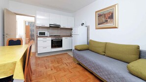 A compact living space with a kitchenette, a dining area, and a sofa. - Holiday apartment with air conditioning and garden (Jadranovo)