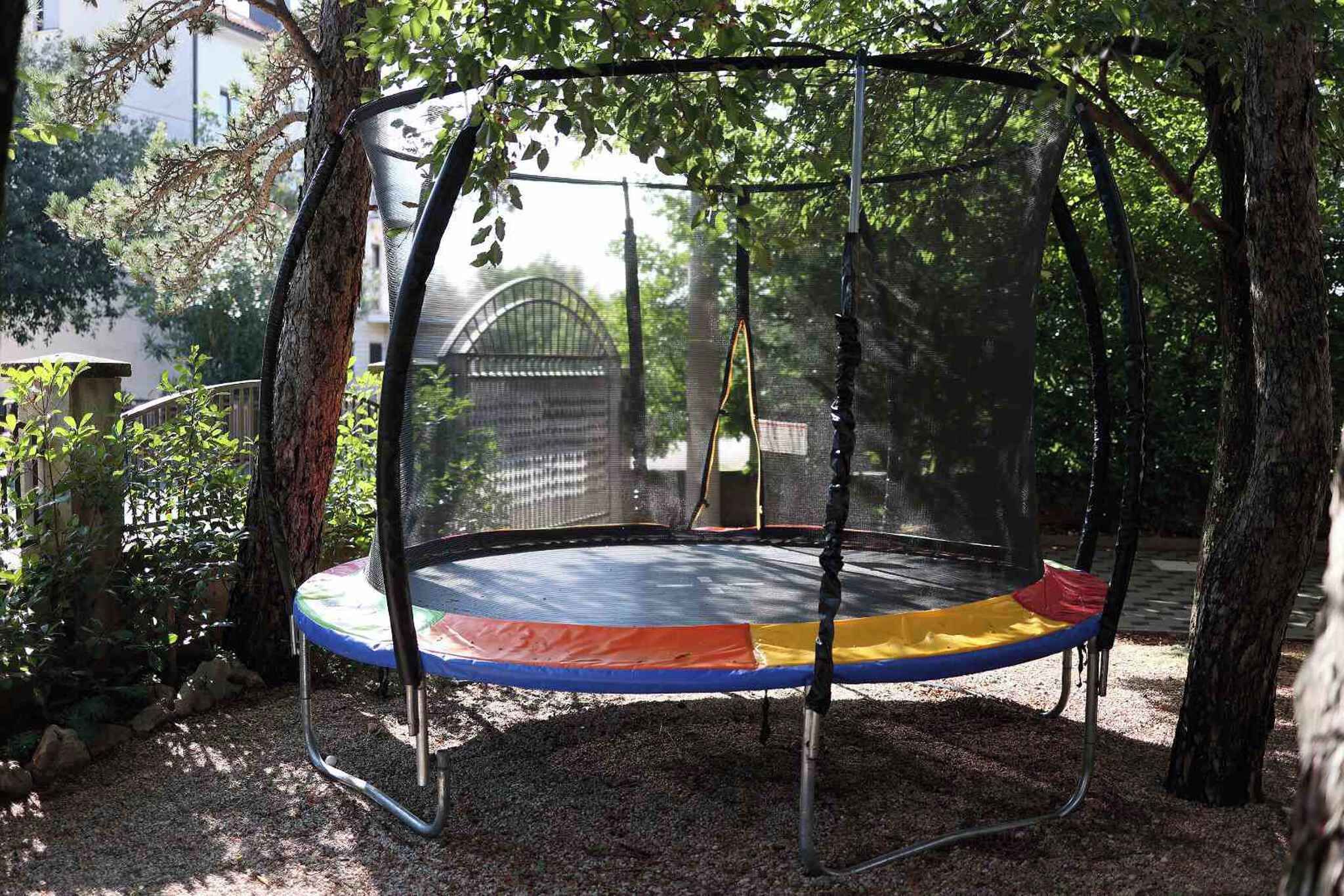 A trampoline in a covered area surrounded by trees.