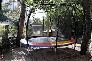 Ein Trampolin in einem überdachten Bereich, umgeben von Bäumen.