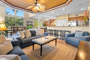 Ein geräumiges Wohnzimmer mit einer Couch, einem Couchtisch und Blick auf die Küche.