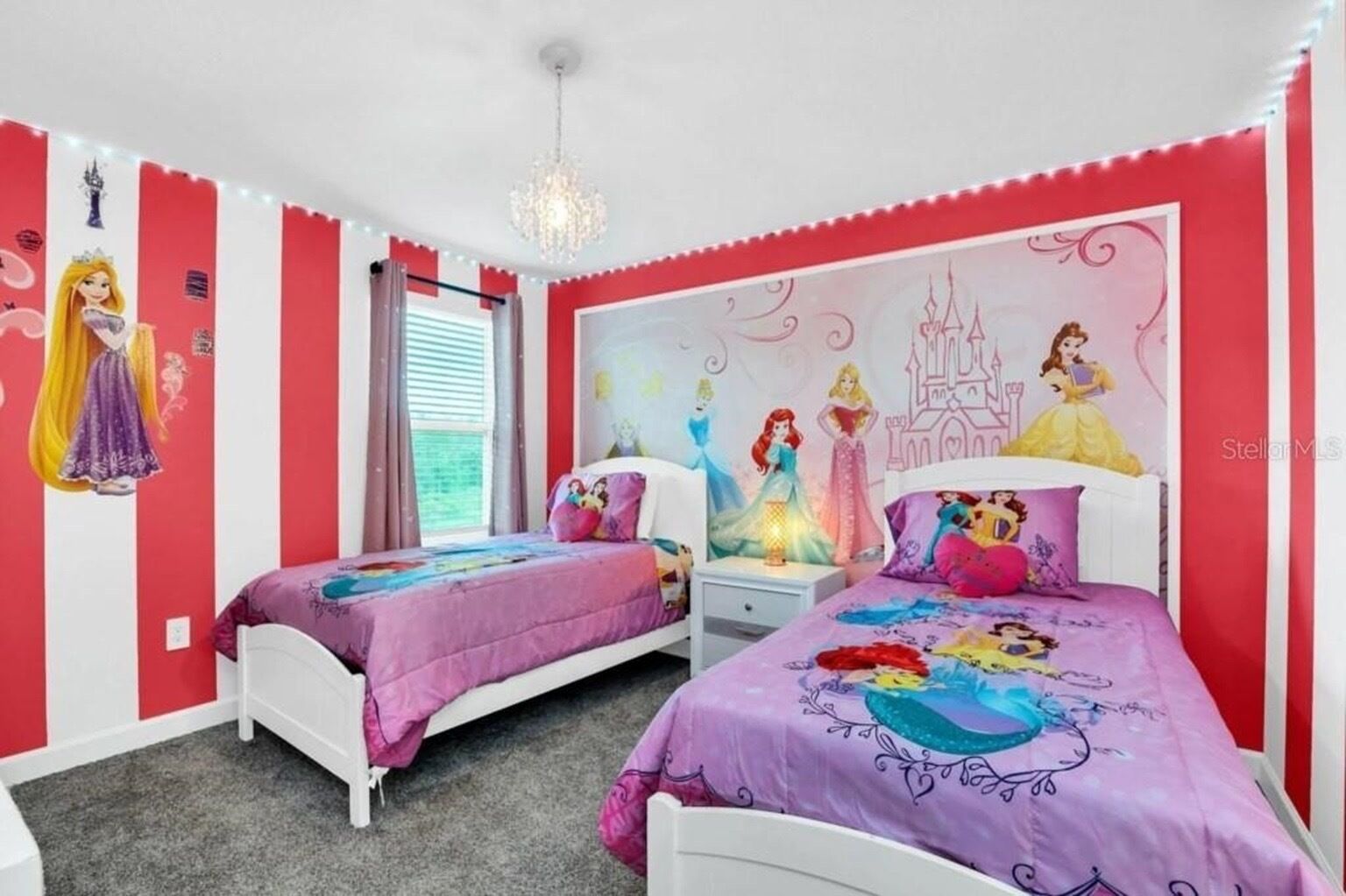 Ein Schlafzimmer mit zwei Betten, einer Chandelieber und Dekorationen zum Thema Disney-Prinzessinnen.