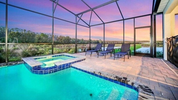 A pool with a hot tub, lounge chairs, and a view of the landscape. - Beautiful 9-bedroom house with AC in serene Kissimmee , Bring the whole Family ! (Kissimmee)