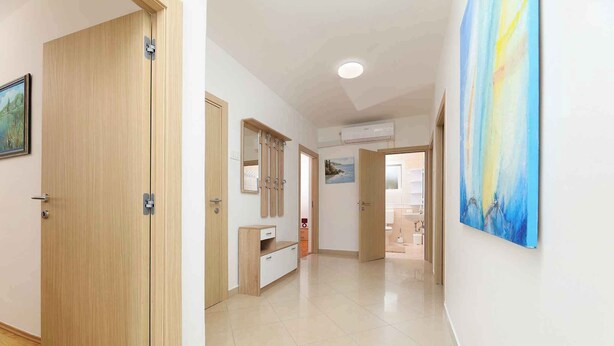 Um corredor com portas de madeira, um armário branco e um quadro na parede.