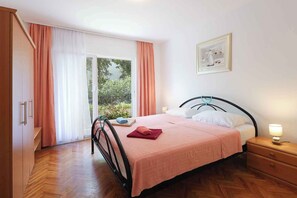 Ein Schlafzimmer mit Bett, Nachttisch, Kleiderschrank und einem Fenster mit Vorhängen.