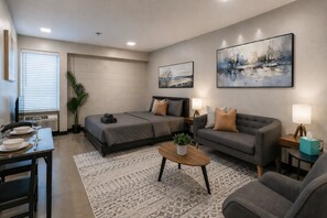 Ein modernes Hotelzimmer mit Bett, Sofa, Esstisch und Kunstwerken an den Wänden.