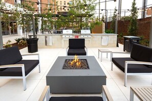 Eine Terrasse im Freien mit Feuerstelle, Sitzgelegenheiten und Grillbereich.