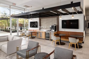 Ein modernes Interieur mit einer Couch, Sesseln, einer Kaffeemaschine und einem Fernseher.