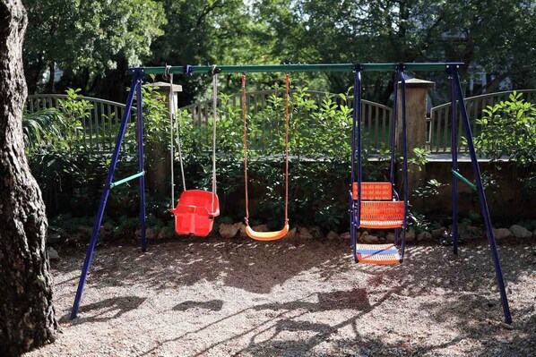 A playground with swings and a climbing structure. - Holiday flat pleasantly overlooking the courtyard and garden (Jadranovo)