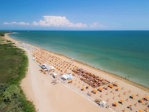 Ein Strand mit Reihen von Sonnenschirmen und Liegestühlen, einem Rettungsturm und freiem Blick auf den Ozean.