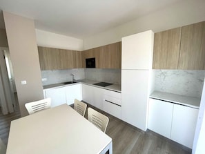 Eine moderne Küche mit weißen Schränken, einer Marmor-Spritzschutzwand und einem eingebauten Backofen.
