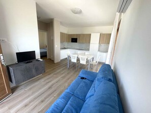 Ein modernes Wohnzimmer mit einem blauen Sofa, einem Fernseher und einem kleinen Tisch.