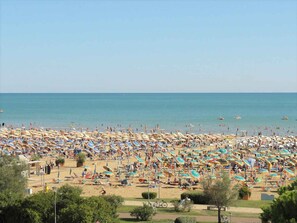 Une plage dotée de nombreux parasols et de chaises longues, ce qui indique qu’il s’agit d’un complexe hôtelier balnéaire.