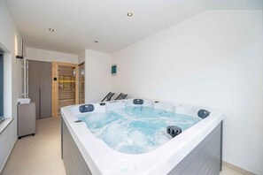 A modern bathroom with a large jacuzzi, a shower area, and a glass-enclosed toilet. - Holiday home with hot tub and terrace (Sukošan)
