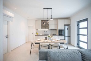 A modern kitchen with a dining area, built-in cabinets, and pendant lighting. - Holiday home with hot tub and terrace (Sukošan)