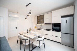 A modern kitchen with a dining area, stainless steel appliances, and pendant lighting. - Holiday home with hot tub and terrace (Sukošan)