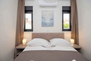 A hotel room with a bed, two bedside lamps, a painting above the bed, and a window with curtains. - Holiday home with hot tub and terrace (Sukošan)