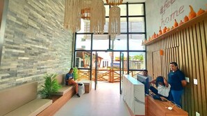 A reception area with a modern design, featuring a brick wall, a wooden reception desk, and hanging light fixtures. - Sunny Hall By Flat na Praia (Ipojuca)